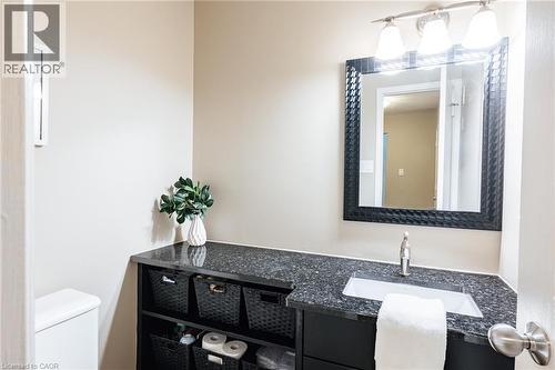 Bathroom vanity featuring a dark speckled countertop, integrated sink, and black framed mirror - 28 Mcgibbon Court, Kitchener, ON 