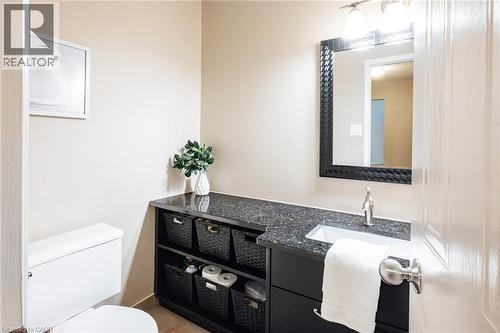 Bathroom vanity featuring a dark countertop, an undermount sink with a single-handle faucet, and black cabinetry with woven storage baskets - 28 Mcgibbon Court, Kitchener, ON 