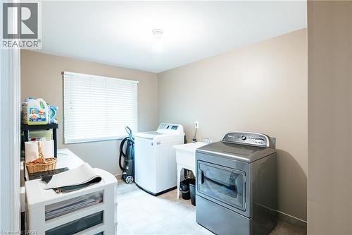 Dedicated laundry room featuring a utility sink, window with blinds, and tile flooring - 28 Mcgibbon Court, Kitchener, ON 