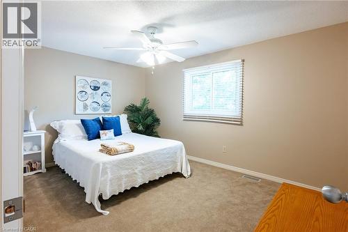 Carpeted bedroom featuring neutral-toned walls, a window with blinds, and a ceiling fan with integrated lighting - 28 Mcgibbon Court, Kitchener, ON 