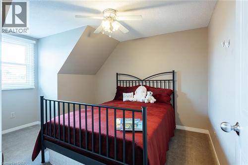 Carpeted room featuring a ceiling fan with light fixture, a window with horizontal blinds, and an angled wall - 28 Mcgibbon Court, Kitchener, ON 