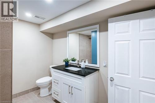 Bathroom featuring a white vanity with a black countertop, undermount sink, and chrome hardware - 28 Mcgibbon Court, Kitchener, ON 