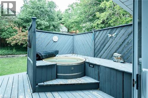 Private hot tub area featuring a wood-plank deck, built-in wooden hot tub, and surrounding slatted privacy fencing - 28 Mcgibbon Court, Kitchener, ON 