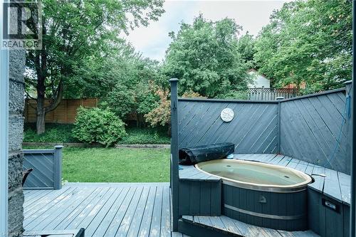 Expansive backyard deck featuring a sunken hot tub, privacy screening, wood fencing, and a manicured lawn - 28 Mcgibbon Court, Kitchener, ON 