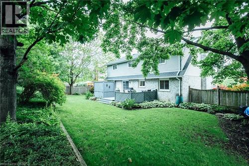 Expansive backyard featuring a lush lawn, mature trees, a multi-level deck, and established perennial garden beds - 28 Mcgibbon Court, Kitchener, ON 