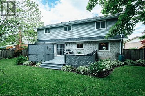 Rear exterior featuring a grey wood-finish multi-level deck with privacy screens, brick and siding facade, and multiple windows - 28 Mcgibbon Court, Kitchener, ON 