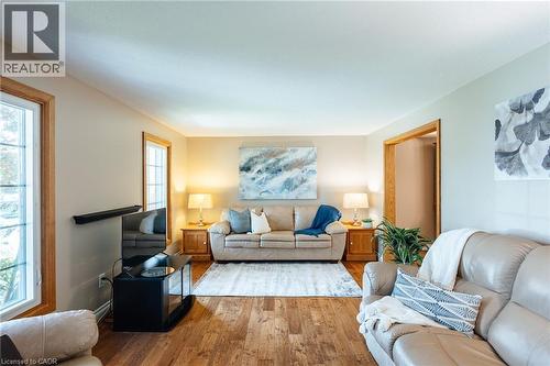 Spacious living area featuring wood-finish flooring, neutral wall tones, and natural light from multiple windows with wood trim - 28 Mcgibbon Court, Kitchener, ON 