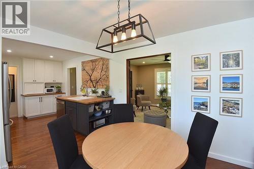 Open-concept dining area featuring a wood-finish round table and a contemporary black metal pendant light fixture - 8 Sheridan Boulevard, Simcoe, ON 