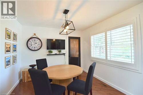 Dining area featuring a light wood-finish table, dark wood-finish flooring, and a modern geometric light fixture - 8 Sheridan Boulevard, Simcoe, ON 