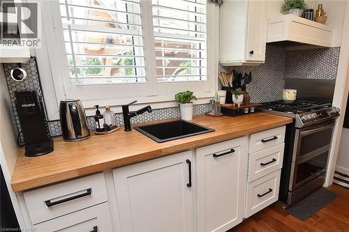Kitchen featuring white shaker cabinetry, wood-finish countertops, and a black undermount sink with a matte black faucet - 8 Sheridan Boulevard, Simcoe, ON 