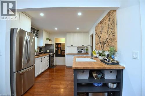 Kitchen featuring wood-finish flooring, white cabinetry, stainless steel appliances, and wood countertops - 8 Sheridan Boulevard, Simcoe, ON 