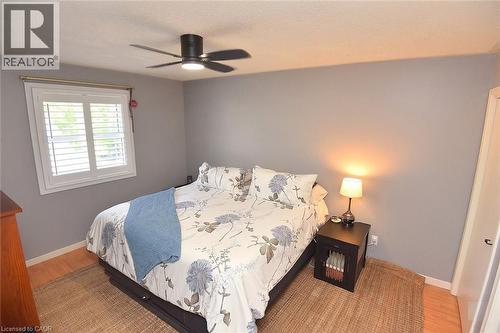 Bedroom featuring a ceiling fan with integrated lighting, a window with white plantation shutters, light wood-finish flooring, and neutral wall tones - 8 Sheridan Boulevard, Simcoe, ON 