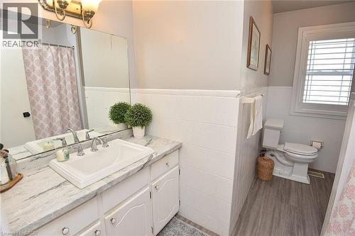 Bathroom featuring a white vanity with an integrated sink, a faux marble countertop, and chrome fixtures - 8 Sheridan Boulevard, Simcoe, ON 