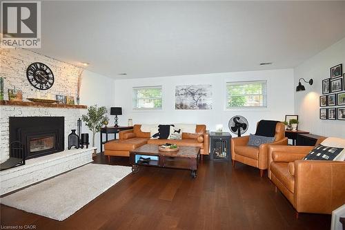 Living area featuring rich wood-finish flooring, a white brick fireplace with a wood mantle, recessed lighting, and multiple windows providing natural light - 8 Sheridan Boulevard, Simcoe, ON 