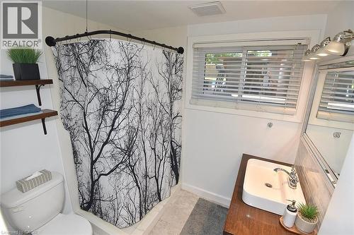 Bathroom featuring a window with blinds, a white rectangular vessel sink set on a wood-finish vanity, and a toilet - 8 Sheridan Boulevard, Simcoe, ON 