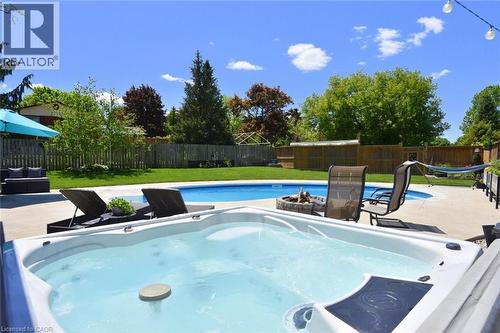 Outdoor spa with integrated seating, concrete surround, and adjacent swimming pool - 8 Sheridan Boulevard, Simcoe, ON 