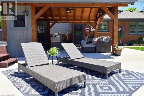 Outdoor living area featuring a custom timber-framed pergola with ceiling fan, providing shade over a concrete patio - 8 Sheridan Boulevard, Simcoe, ON 