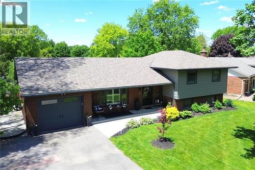 Brick and siding exterior residence featuring a dark gray garage door, a covered front entry, and a paved driveway - 8 Sheridan Boulevard, Simcoe, ON 