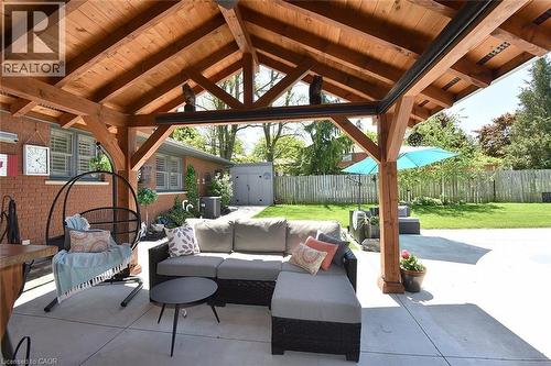 Expansive outdoor living area featuring a vaulted wood-beam patio cover, concrete hardscaping, a manicured lawn, and a privacy fence - 8 Sheridan Boulevard, Simcoe, ON 