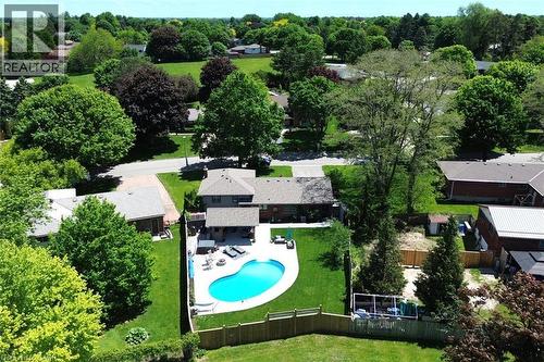 Rear exterior featuring a freeform swimming pool, concrete patio, and a privacy fence - 8 Sheridan Boulevard, Simcoe, ON 