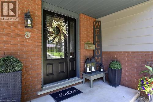 Brick and siding exterior featuring a black front door with decorative glass, a complementary storm door, and an exterior wall lantern - 8 Sheridan Boulevard, Simcoe, ON 