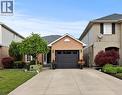 Brick facade home with an attached garage, paved driveway, mature landscaping, and an arched entry porch - 40 Bridgette Drive, Hamilton, ON 