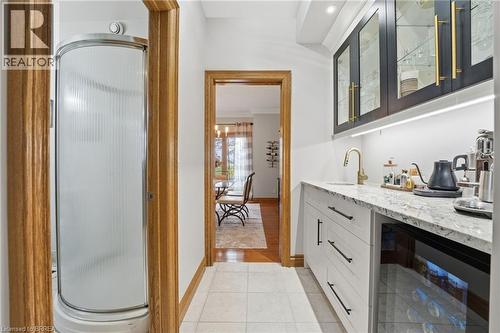 Custom built-in wet bar featuring white cabinetry, a granite-finish countertop, and a brass-finish faucet - 271 Windham Rd 14, Simcoe, ON 