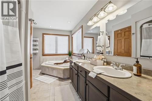 Bathroom featuring a dual vanity with undermount sinks, a built-in tub with a tiled surround, a large mirror, and recessed lighting - 271 Windham Rd 14, Simcoe, ON 