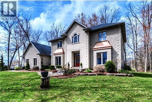Stately residence featuring a stone and stucco exterior, multiple gables, a prominent entry, and a front yard with mature landscaping - 271 Windham Rd 14, Simcoe, ON 