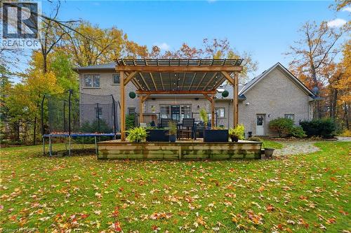 Spacious rear yard featuring a large wooden deck with a pergola, mature trees, and a brick exterior - 271 Windham Rd 14, Simcoe, ON 