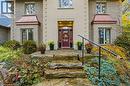 Exterior featuring a red entry door, stone steps, metal handrail, light-colored brick facade, and copper-colored bay window awnings - 271 Windham Rd 14, Simcoe, ON 