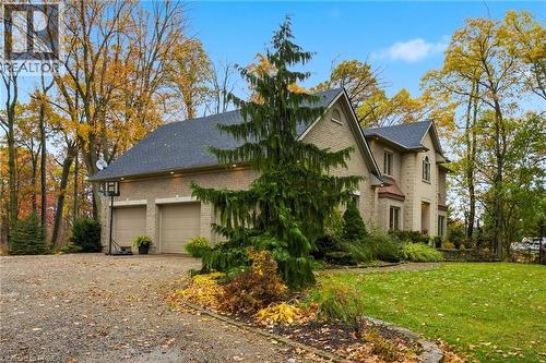 Stone and brick exterior residence featuring a multi-car garage with two bays, a shingled roof, a gravel driveway, and mature landscaping - 271 Windham Rd 14, Simcoe, ON 