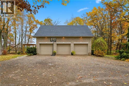 Three-car garage with light-colored brick exterior, dark shingle roof, and complementary garage doors - 271 Windham Rd 14, Simcoe, ON 