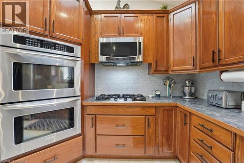 Kitchen featuring stainless steel double wall ovens, a gas cooktop, built-in microwave, wood cabinetry, and a tile backsplash - 271 Windham Rd 14, Simcoe, ON 