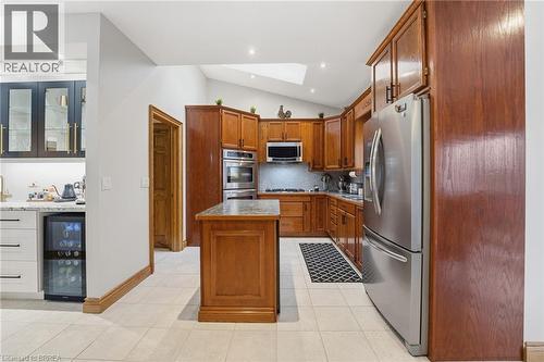 Kitchen featuring wood cabinetry, stainless steel appliances, a center island with a stone countertop, recessed lighting, and tiled flooring - 271 Windham Rd 14, Simcoe, ON 