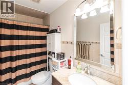 Bathroom featuring a vanity with a light-colored countertop and undermount sink, a framed mirror, and a chrome light fixture - 