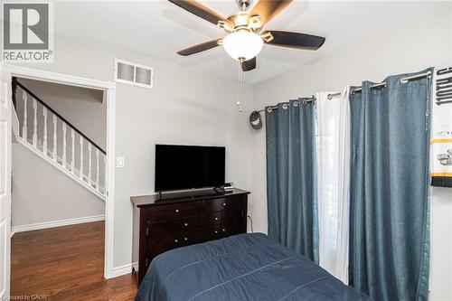 Interior space with wood-finish flooring, a ceiling fan with integrated lighting, and a doorway opening to a staircase with white spindles and a dark handrail - 38 Fairleigh Avenue N, Hamilton, ON 