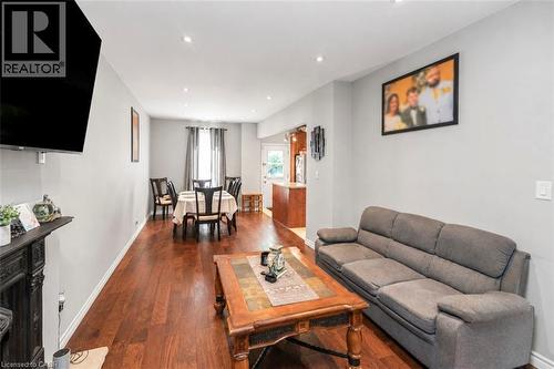 Open-concept living and dining area featuring wood-finish flooring, recessed lighting, and light gray wall tones - 38 Fairleigh Avenue N, Hamilton, ON 