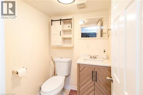 Bathroom featuring a floating vanity with a marble-finish countertop, undermount sink, and a modern barn door-style medicine cabinet with open shelving - 38 Fairleigh Avenue N, Hamilton, ON 