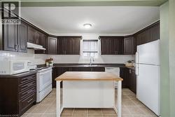 Kitchen featuring dark wood-finish cabinetry, light countertops, white subway tile backsplash, and a central island with a wood-finish top - 