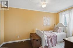 Room featuring wood-finish flooring, a ceiling fan with integrated lighting, a window with curtain rod, white baseboards, and crown molding - 