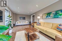 Spacious living area featuring wood-finish flooring, recessed lighting, crown molding, and a large window - 