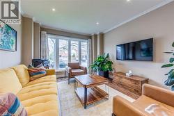 Living area featuring a large bay window, recessed lighting, crown molding, and wood-finish flooring - 