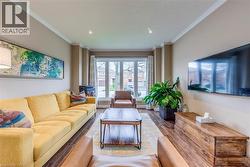 Living area featuring crown molding, recessed lighting, wood-finish flooring, a large bay window, and a wall-mounted media console - 