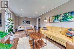Living area featuring wood-finish flooring, recessed lighting, crown molding, and a large window with white trim - 
