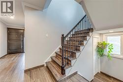 Wood-finish staircase with wrought iron balusters and dark wood newel post - 