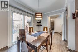 Contemporary dining space featuring wood-finish flooring and a drum pendant light fixture - 