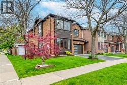 Brick exterior with dark trim accents, featuring a modern garage door and an established front lawn - 