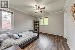 Bedroom featuring wood-finish flooring, two windows, and a ceiling fan with light fixture - 