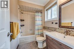 Bathroom featuring a wood-finish vanity with an integrated sink, a tiled backsplash, and a window for natural light - 